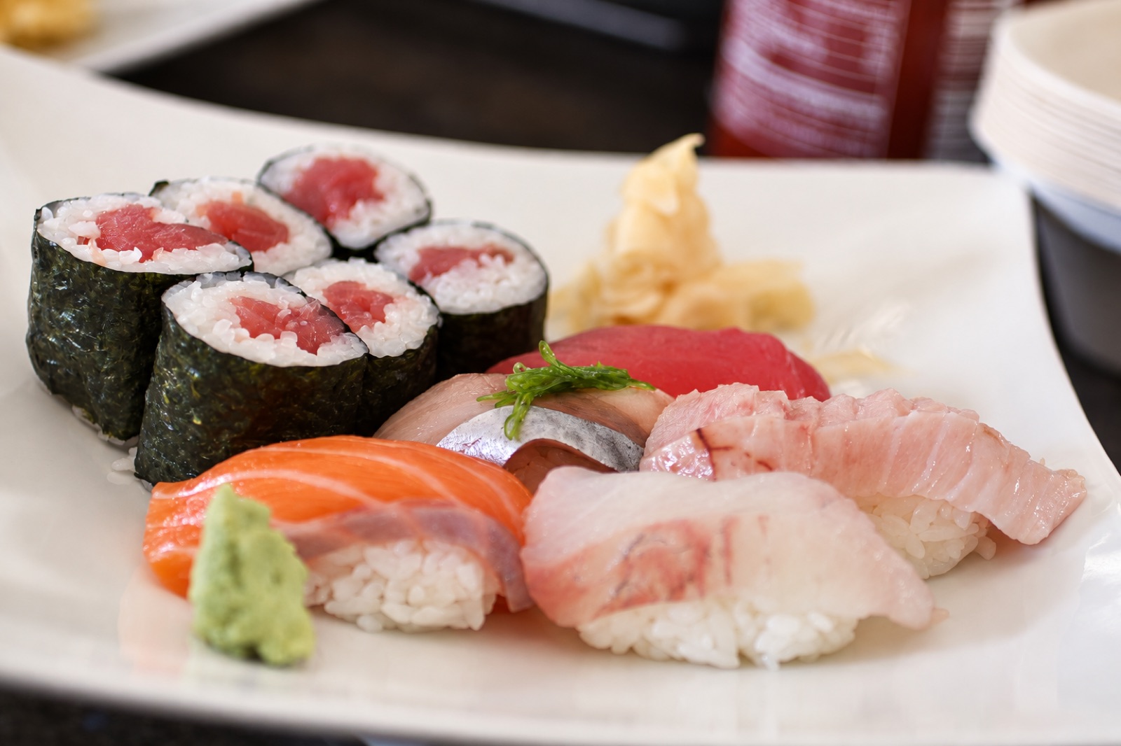 Salmon and silver-skinned nigiri with tuna maki on a white plate at Umi